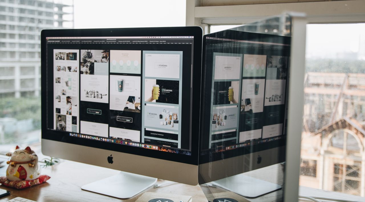 our-story Dual monitors on a desk, showcasing web design in a modern office setting.